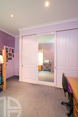 Custom-built wardrobe with floor-to-ceiling sliding doors, hanging rails, shelves, and drawers
